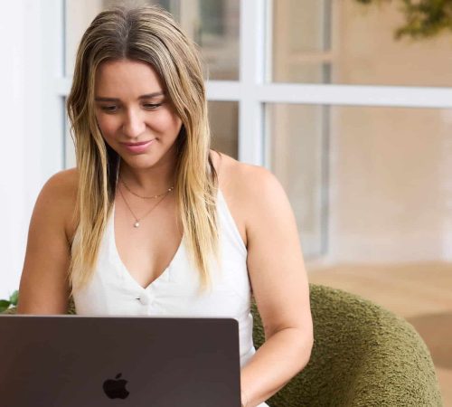 Young woman working on a laptop in a modern office setting.